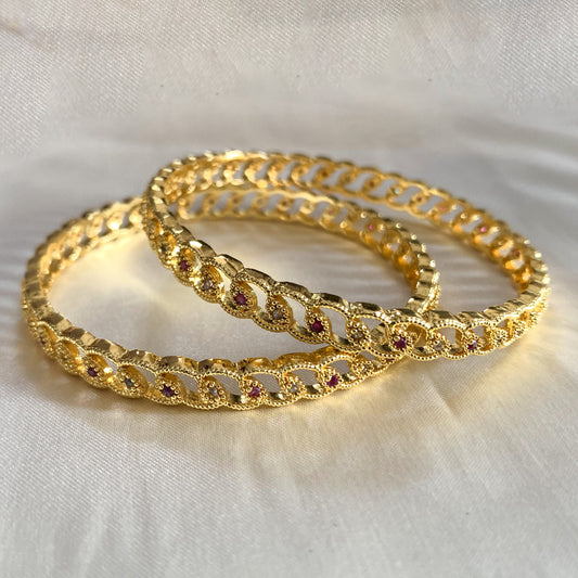 Elegant gold-plated bangles featuring intricate loop patterns and pink stones – ethnic accessory for women
