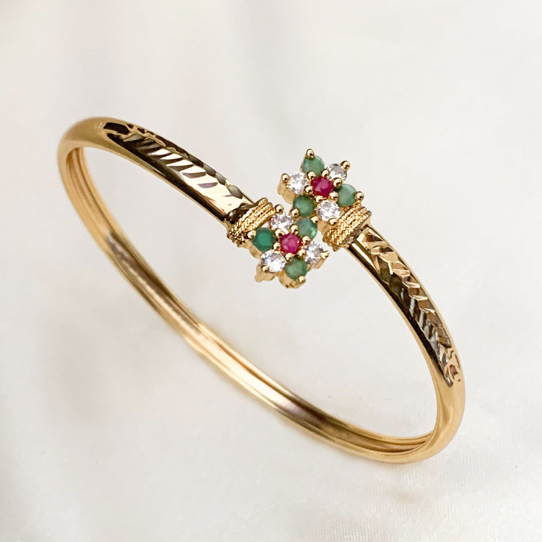 Gold bracelet with gemstone accents on a light background