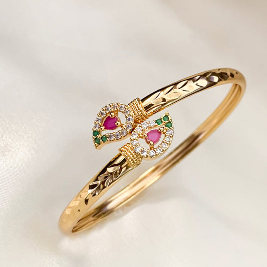 Gold bracelet with floral-shaped gemstones on a light background