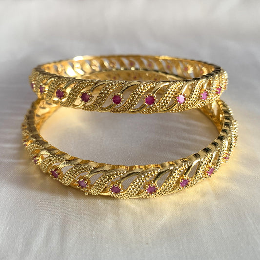 Twisted gold-plated bangles with pink stone detailing – traditional and party wear jewelry for women
