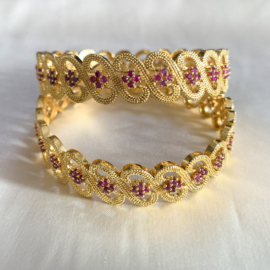Women's gold-plated bangles featuring infinity motifs and ruby-red stones – perfect for weddings and cultural celebrations