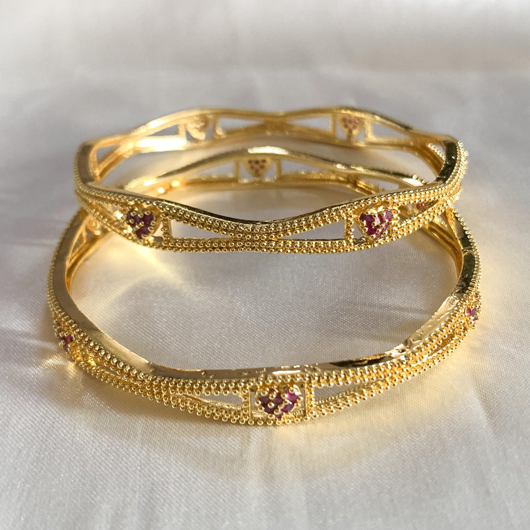 Charming gold-plated bangles with heart-shaped pink accents – feminine and stylish accessory for cultural events
