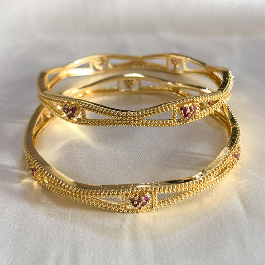 Charming gold-plated bangles with heart-shaped pink accents – feminine and stylish accessory for cultural events