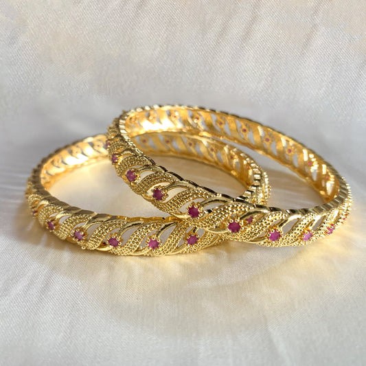 Elegant gold-plated bangles featuring a twisted design and pink stones – perfect for festive and ethnic occasions