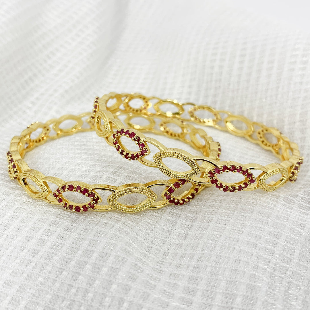 Elegant gold-plated bangles with sparkling pink crystal detailing – stylish accessory for traditional occasions
