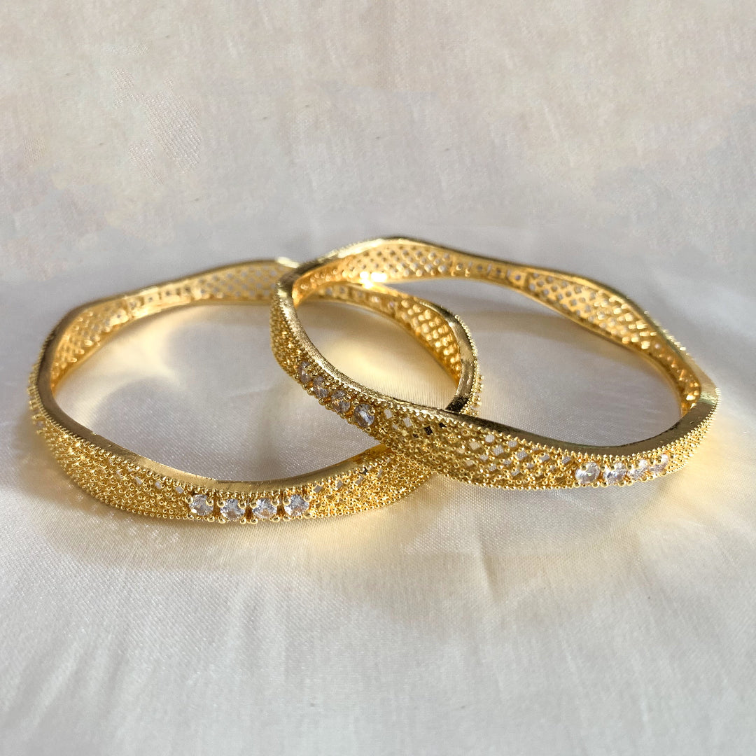 Elegant gold bangles with white stone detailing – stylish and sophisticated ethnic jewelry for weddings and parties