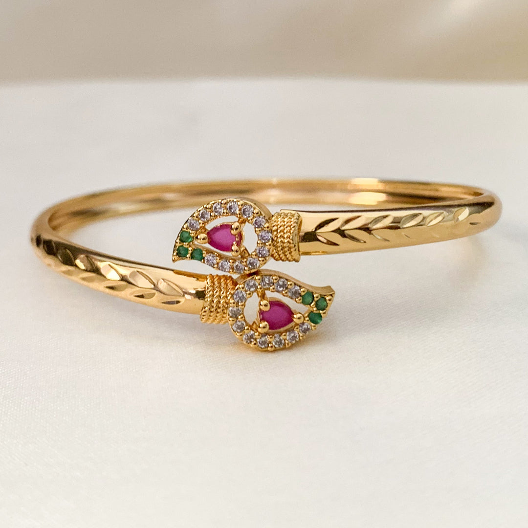 Gold bracelet with gemstone accents on a light background