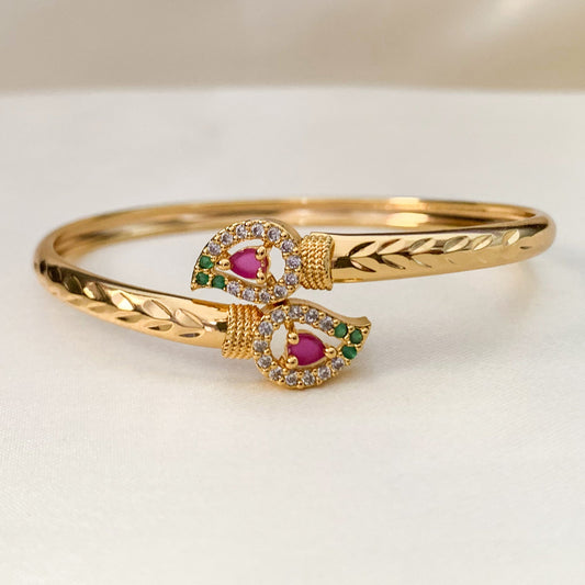 Gold bracelet with gemstone accents on a light background