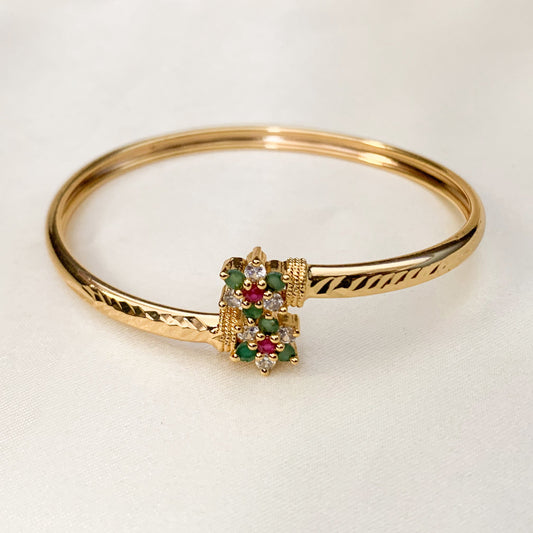 Gold bracelet with gemstone clasp on a light background