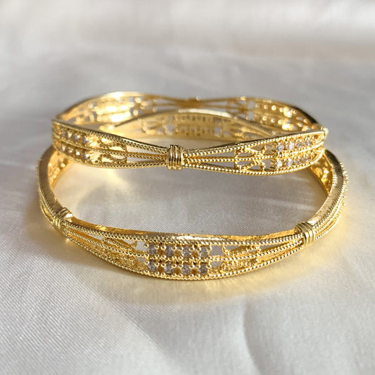 Gold-plated ethnic bangles featuring intricate criss-cross design and sparkling white stones – ideal for festive and bridal wear