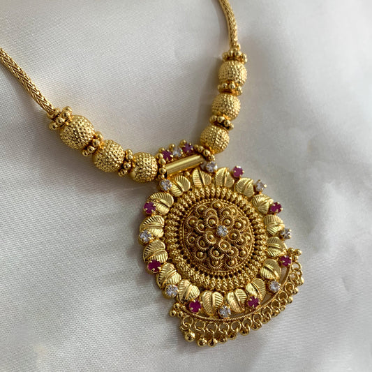 Gold-plated ethnic necklace featuring a detailed pendant and ruby-colored stones – perfect for weddings and traditional occasions