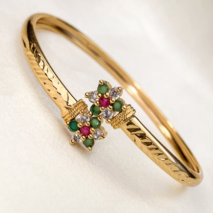 Gold bracelet with gemstone embellishments on a light background