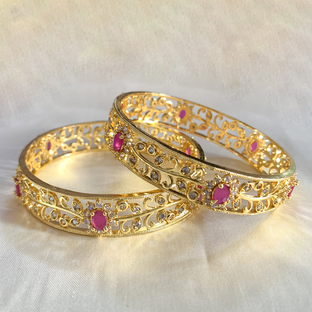 Royal gold-plated bangles with pink stone centerpieces and CZ detailing – luxurious bridal and ethnic wear jewelry