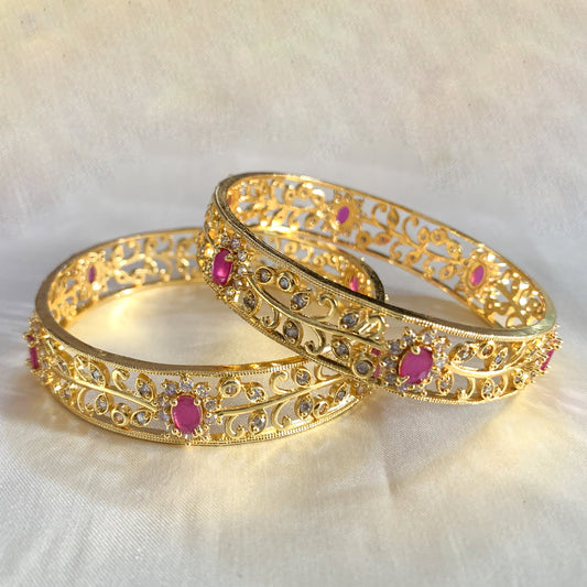 Royal gold-plated bangles with pink stone centerpieces and CZ detailing – luxurious bridal and ethnic wear jewelry