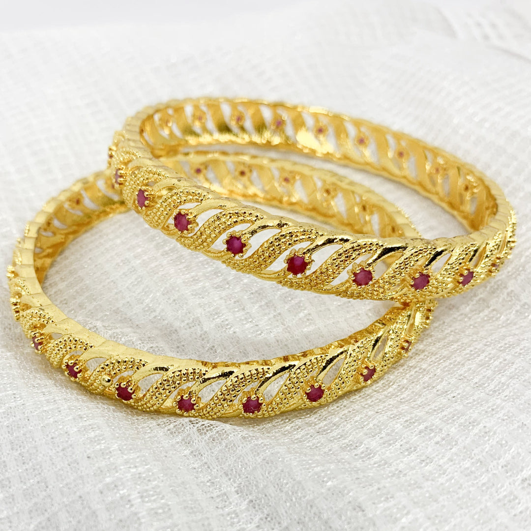 Stylish twisted bangles in gold plating with pink accents – versatile accessory for traditional and modern outfits