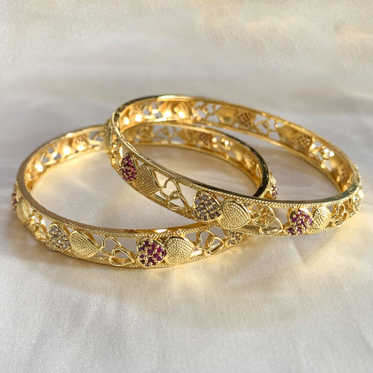 Traditional gold-plated bangles featuring heart motifs with ruby and crystal accents – perfect for festive and bridal wear