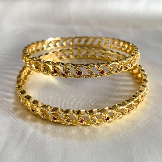 Traditional gold-tone bangles with pink gemstone accents and loop detailing – perfect for weddings and cultural celebrations